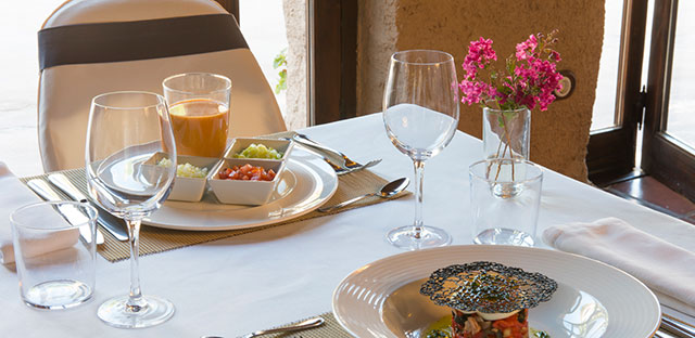 Teller mit verschiedenen Gourmet-Vorspeisen auf einem elegant gedeckten Restauranttisch für zwei Personen.