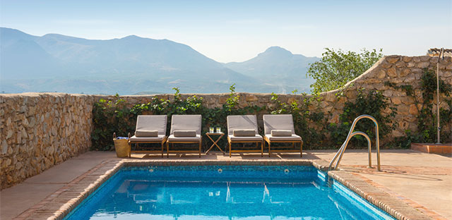 Four comfortable lounge chairs at one end of the outdoor pool with the Sierra Arana in the background.