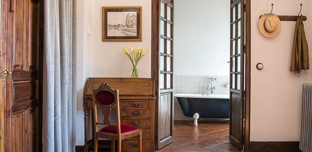 An opened glass panel double door in room La Terraza offering a peek into the bathroom with a cast iron bathtub.